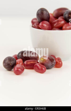 lila Trauben Vs lila Gummibärchen - Entscheidung zwischen gesunde Ernährung oder Junk-Food snack Stockfoto