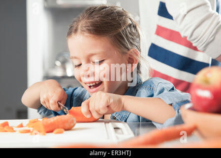 Kleines Mädchen schneiden Möhren in Küche Stockfoto