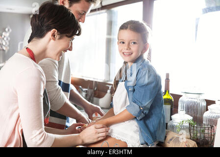 Familie Zeit miteinander zu verbringen, in Küche, Mädchen sitzen auf Zähler Holding Mutters Hände Stockfoto