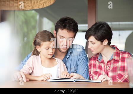 Kleines Mädchen mit ihren Eltern lesen Stockfoto