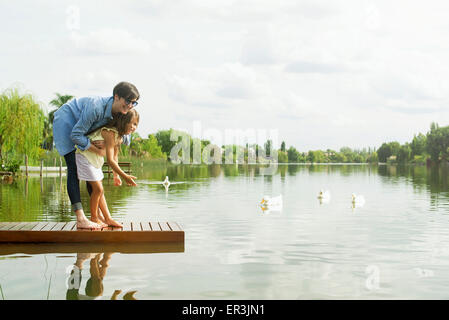 Mutter und junge Tochter füttern Enten am See Stockfoto