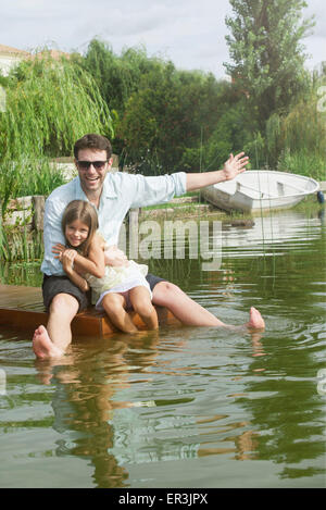 Vater und Tochter sitzen auf Dock, Porträt Stockfoto