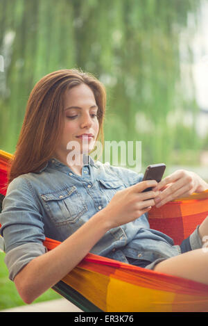 Frau zum Entspannen in der Hängematte mit smartphone Stockfoto