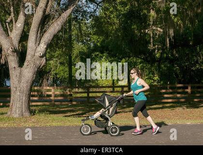 junge Frau Joggen in einem Park und einen Kinderwagen zu schieben. Stockfoto