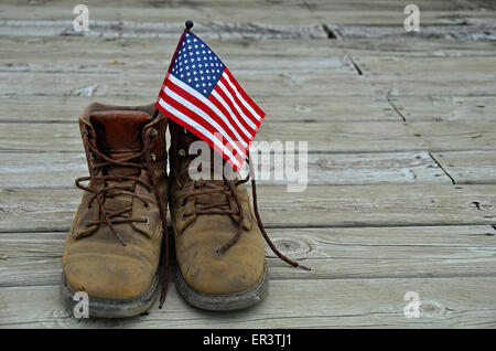 Amerikanische Flagge in einem Paar von Arbeitsstiefeln auf Holzdeck. Stockfoto