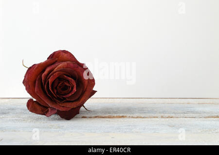 Verwelkte rote rose auf einem Holzregal. Stockfoto