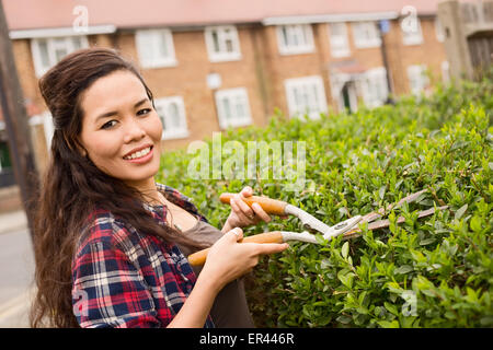 junge Frau, die ihre Hecke schneiden Stockfoto