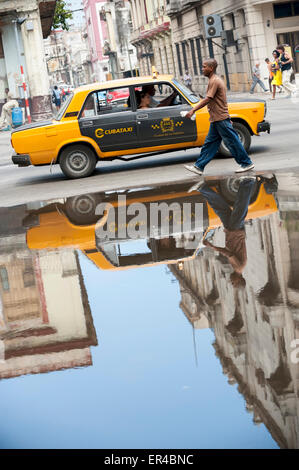 Havanna, Kuba - Juni 2011: Vintage russischen Lada Taxi Auto spiegelt neben vorbeifahrenden Fußgänger in einer Pfütze auf einer Straße im Centro. Stockfoto