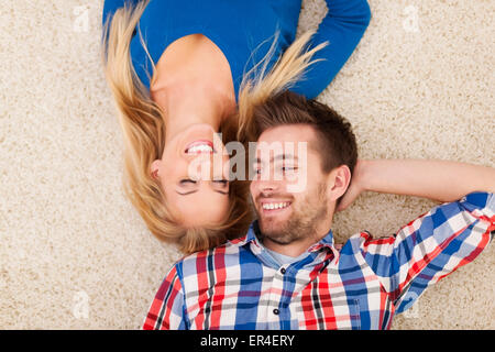 Süße junge Paar liegen auf Teppich und schauen einander Stockfoto