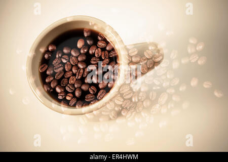 Milchkaffee Tasse Stand auf einem Tisch über dunkle verrosteten Kaffeebohnen Textur. Doppelbelichtung Foto mit Vintage-Stil Foto Filter e Stockfoto