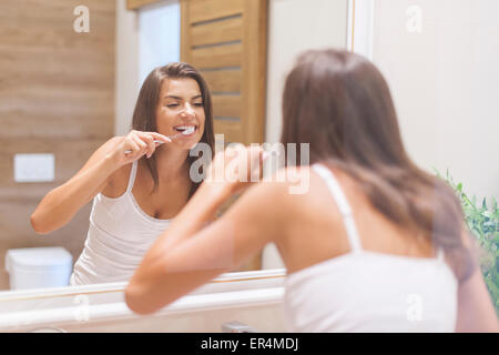 Frau Zähneputzen vor Spiegel. Foto durch Glas. Debica, Polen Stockfoto