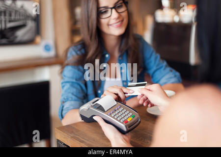 Lächelnde Frau Kaffee per Kreditkarte bezahlen. Krakau, Polen Stockfoto
