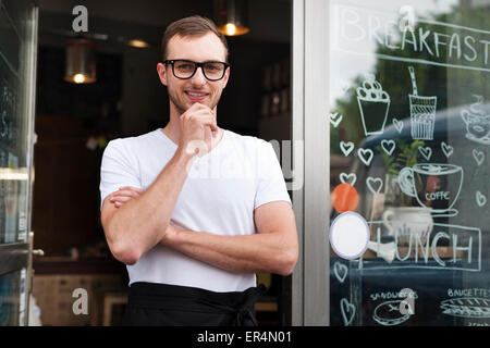 Porträt von lächelnden männlichen Kellner vor dem Café. Krakau, Polen Stockfoto