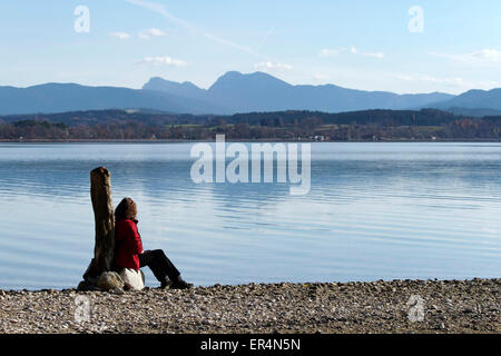 Frau sitzt auf den Felsen mit Blick auf den See, Chiemsee Chiemgau oberen Bayern Deutschland Europa Stockfoto