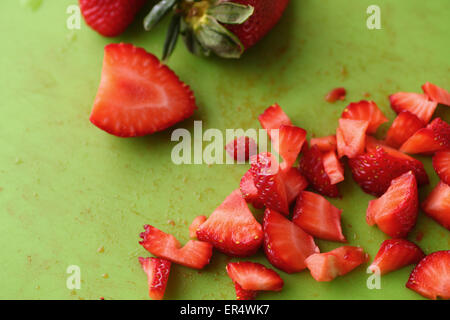 Frische Erdbeeren, gehackt, ganz und halb auf einer grünen Schneidebrett Stockfoto