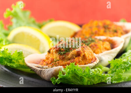 Gefüllte erfahrene Muscheln mit Romaine Kopfsalat und Zitrone Keile auf einem rustikalen Teller garniert Stockfoto