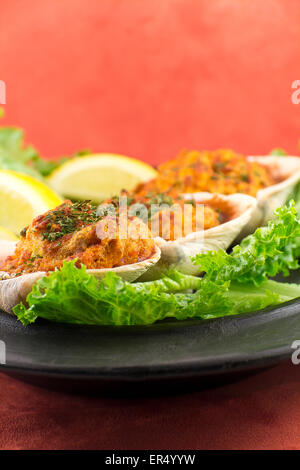 Gefüllte erfahrene Muscheln mit Romaine Kopfsalat und Zitrone Keile auf einem rustikalen Teller garniert Stockfoto