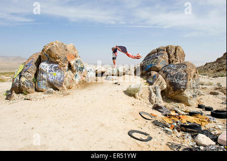 Mädchen in Cowboy-Hut und Sterne und Streifen Jacke Fliegende Sterne und Streifen Fahne in den Wind, Mojave-Wüste, Southern California. Stockfoto