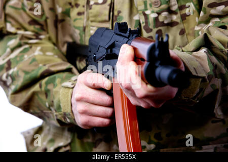 Mann in Kampfuniform holding Aks-47u Quartal Kampf Kalaschnikow Gewehr Naheinstellung auf Sicherheit-Wahlschalter Stockfoto
