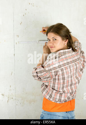 Junge Frau mit Messung der Band stehen auf der Vorderseite der Mauer Stockfoto