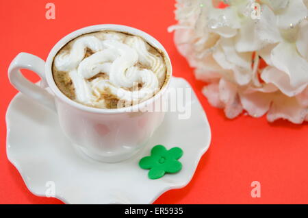 Tasse Kaffee mit Schlagsahne auf einem roten Tisch Stockfoto