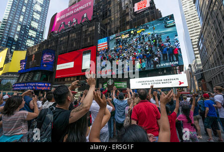 Touristen in Times Square New York City gerade sich auf einem riesigen LED-Bildschirm Stockfoto