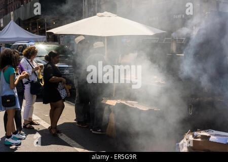 Ein Kreditor Ruckhuhn raucht und raucht die Luft bei einem Straßenfest im Stadtteil Chelsea in New York auf Montag, 25. Mai 2015. (© Richard B. Levine) Stockfoto
