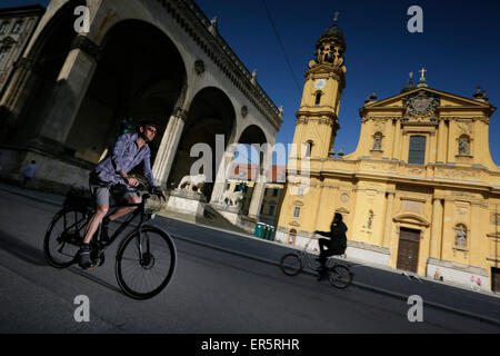 Mann mit einem e-Bike crossing Odeonsplatz, München, Oberbayern, Deutschland Stockfoto