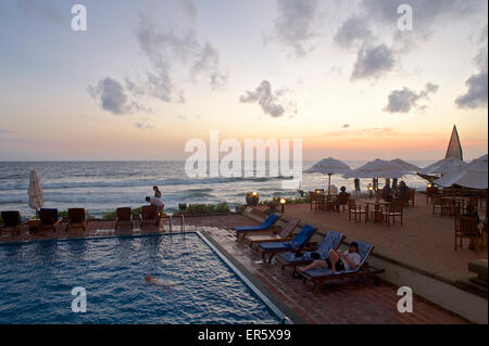 Menschen rund um den Pool mit Blick aufs Meer in der Abenddämmerung an der Galle Face Hotel, Colombo, Sri Lanka Stockfoto