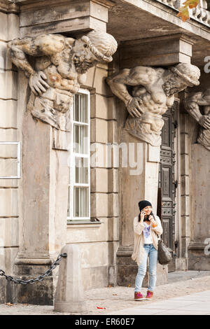 Ein Student steht unter einer Fassade eines mythischen Mannes geschnitzt im Gebäude neben dem Haupttor der Universität Warschau Stockfoto