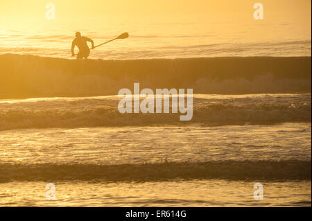 Ein goldener Morgen an Floridas Ostküste in Ponte Vedra Beach als Stand-up Paddleboarder navigiert den Ozean schwillt. Stockfoto