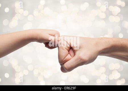 Vater und Sohn Stanzen Fäuste für Abkommen auf schönen Weihnachten Lichter Hintergrund. Stockfoto