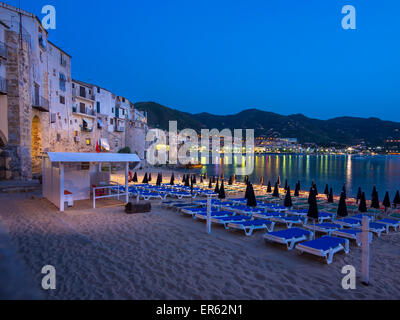 Strandkörbe auf die Bucht von Cefalu, mittelalterliche Häuser am Strand von Cefalù hinter Cefalù, Provinz von Palermo, Sizilien, Italien Stockfoto