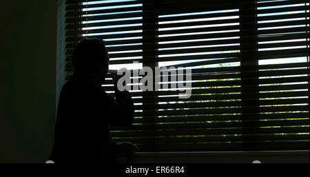 Silhouette einer unerkennbar Person zurück Blick aus dem Fenster blind. Stockfoto