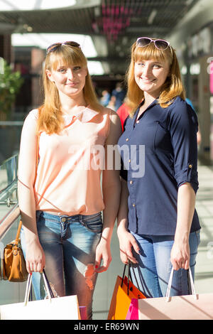 Junge Zwillinge Mädchen viel Spaß halten ihre Einkaufstüten. Zwei kaukasischen Schwestern lächelnd in der Shopping mall Stockfoto
