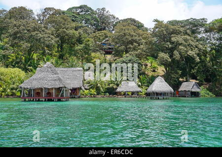 Waterfront Ecolodge mit strohgedeckten Hütte Overwater und üppiger tropischer Vegetation auf dem Land, Karibikseite von Panama, Central Stockfoto