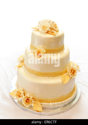 Hochzeitstorte. 3-Stufen abgedeckt Elfenbein Fondant mit Perle Spray und gelb/Gold Zucker Rosen gespritzt Stockfoto