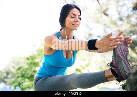 Sportliche fröhliche Frau, die Beine im Freien im park Stockfoto