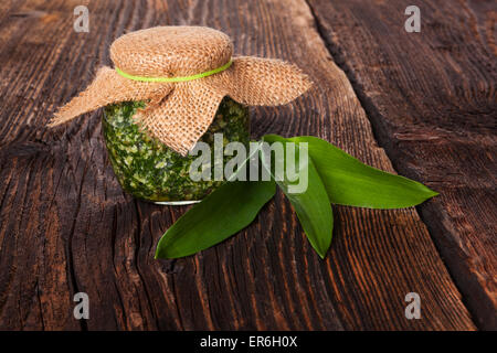 Knoblauch-Pesto im Glas mit frischen Bärlauch-Blätter auf Holz braun strukturierten Hintergrund. Kulinarischen gesunde Ernährung. Stockfoto