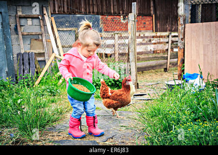 kleines Mädchen vor Bauernhof Hühner füttern Stockfoto