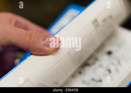 Eine Nahaufnahme von einer Hand Durchblättern der Seiten ein Taschenbuch. Stockfoto
