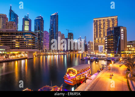 Skyline von Dubai Marina und touristische Boote bei Nacht Dubai Stadt Vereinigte Arabische Emirate VAE Naher Osten Stockfoto