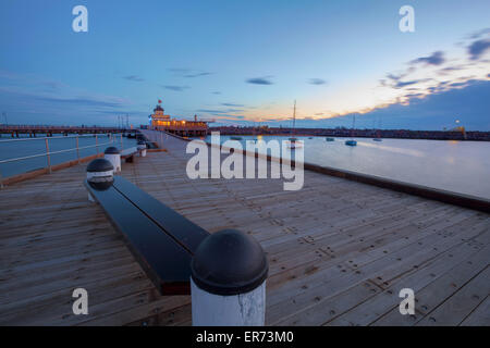 St. Kilda Pier in der Abenddämmerung mit Booten im Hafen und Pavillon in der Ferne. Stockfoto