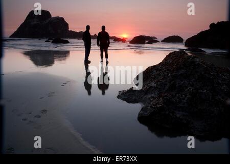 Menschen beobachten den Sonnenuntergang über Meer-Stacks am Strand von Trinidad Bay in California Coastal National Monument in Kalifornien. Das Denkmal besteht aus mehr als 20.000 Inselchen, Felsen, Riffe ausgesetzt und Zinnen erstreckt sich die Länge des Staates zwischen Mexiko und Oregon. Stockfoto