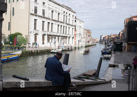 Die Volgalonga, jährliche Ruderregatta in Venedig Italien. 41. jährliche Volgalonga. Mann liest Zeitung in Venedig Italien. Stockfoto