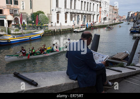 Die Volgalonga, jährliche Ruderregatta in Venedig Italien. 41. jährliche Volgalonga. Mann liest Zeitung in Venedig Italien. Stockfoto