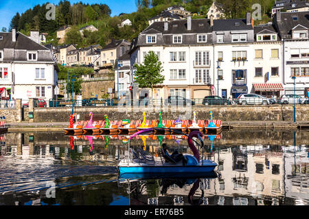 Bouillon (Belgien). Menschen Bootsfahrt eine bunte schwanenförmigen am Fluss; die Stadt im Hintergrund. Blauer Himmel und Reflexionen. Stockfoto