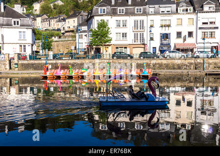 Bouillon (Belgien). Menschen Bootsfahrt eine bunte schwanenförmigen am Fluss; die Stadt im Hintergrund. Blauer Himmel und Reflexionen. Stockfoto