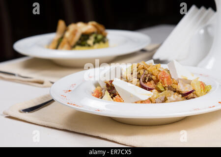 Zubereiteten Speisen in weißen Schalen auf einfache Gedecke serviert am Tisch im Restaurant für zwei Personen Stockfoto