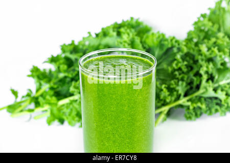 Grüner Smoothie mit Grünkohl im Hintergrund. Stockfoto